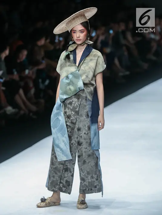 Model memperagakan busana rancangan HUMBANG SHIBORI x PURANA saat Jakarta Fashion Week (JFW) 2019 di Senayan City, Jakarta, Kamis (25/10). HUMBANG SHIBORI x PURANA mengangkat tenun ikat tradisional Humbang Shibori. (Liputan6.com/Faizal Fanani)