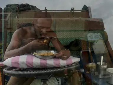 Seorang sopir makan di sebuah truk yang diparkir di terminal di Chennai (19/9/2019). Layanan transportasi darat menyerukan pemogokan satu hari untuk memprotes kenaikan pinalti di bawah Undang-undang Kendaraan Bermotor (Amandemen) yang baru. (AFP Photo/Arun Sankar)