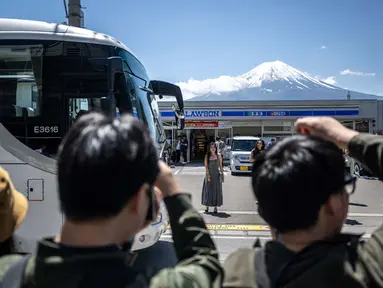 Wisatawan mengambil foto model berlatar Gunung Fuji dari jalan di depan salah satu toko serba ada pada tanggal 3 Mei 2024. (Philip FONG/AFP)