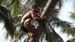 Peserta saat memanjat pohon kelapa di Papeete, Polinesia (15/7). Para peserta yang ikut dalam kejuaraan ini berasal dari Polinesia Prancis yang berada di lima kepulauan yakni Tahiti, Bora Bora, Huahine dan Australes. (AFP Photo/Gregory Boissy)