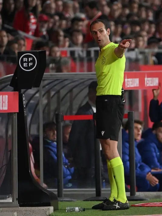 <p>Wasit Melero Lopez meninjau video VAR saat pertandingan sepak bola Liga Spanyol antara Girona dan Atletico Madrid di Stadion Montilivi, Girona, Spanyol, 13 Maret 2023. Gol tunggal Alvaro Morata membawa Atletico Madrid mengalahkan Girona. (LLUIS GENE/AFP)</p>