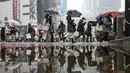 Orang-orang berjalan melintasi persimpangan Shibuya yang terkenal saat salju turun di Tokyo, Kamis (6/1/2022). Hujan salju lebat mendesak orang untuk bersiap menghadapi kemungkinan gangguan lalu lintas dan jalan yang tertutup es. (AP Photo/Kiichiro Sato)