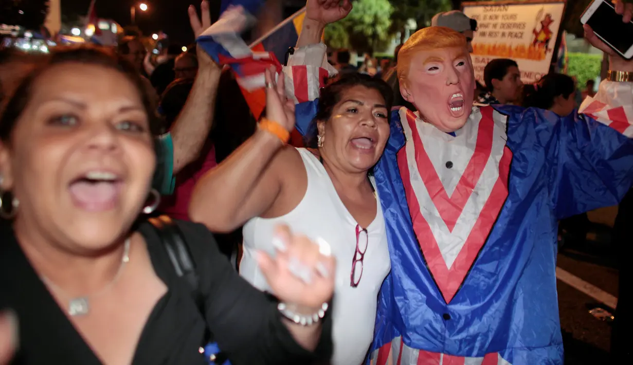 Warga kuba mengenakan kostum berwajah Donald trum saat turun ke jalan merayakan wafatnya Fidel Castro di Miami, AS (26/11). (REUTERS/Javier Galeano)
