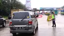 Petugas Kepolisian mengarahkan kendaraan saat penyekatan larangan mudik lebaran di gerbang tol Cikupa, Kabupaten Tangerang, Banten, Kamis (6/5/2021). Penyekatan dilakukan seiring telah diberlakukan larangan mudik Lebaran mulai dari 6 hingga 17 Mei 2021.  (Liputan6.com/Angga Yuniar)