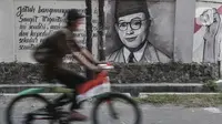 Pesepeda melintasi mural bergambar sosok Bung Hatta di Jalan Pluit Raya III, Jakarta, Minggu (10/8/2020). Mural itu diharapkan menjadi media agar masyarakat selalu mengingat sejarah dan menghargai jasa para pahlawan dalam memerdekakan Tanah Air. (merdeka.com/Iqbal Nugroho)