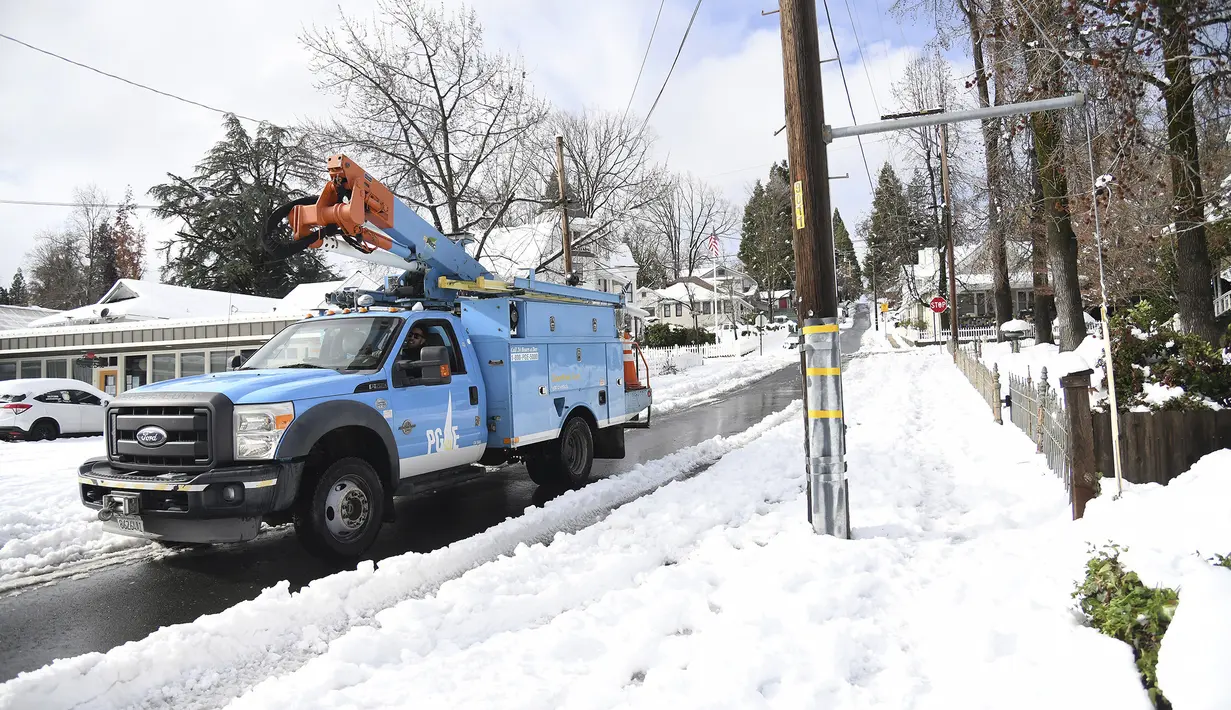 Pekerja Pacific Gas & Electric mulai memeriksa jalur di City of Grass Valley, California, Selasa (28/12/2021). Salju menyebabkan penutupan dan memaksa orang untuk mencari perlindungan di tempat penampungan darurat yang memanas. (Elias Funez/The Union via AP)