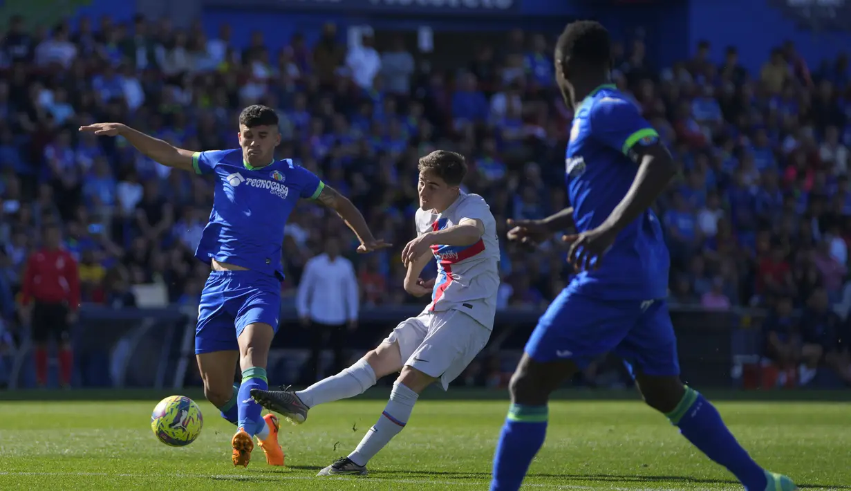 Gelandang Barcelona, Gavi melakukan tembakan ke gawang di depan Munir El Haddadi dari Getafe selama pertandingan lanjutan La Liga Spanyol di stadion Coliseum Alfonso Perez di Getafe, Spanyol, Minggu, 16 April 2023. (AP Photo/Manu Fernandez)
