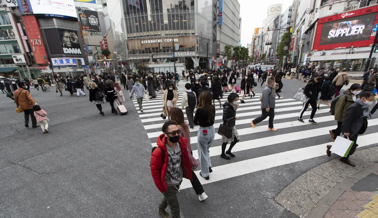Orang-orang, yang mengenakan masker wajah, berjalan melintasi persimpangan di Tokyo (11/12/2020). Tokyo melaporkan 621 kasus COVID-19 baru pada hari Sabtu, 12 Desember, menetapkan level tertinggi baru di ibu kota Jepang. (AP Photo / Hiro Komae)