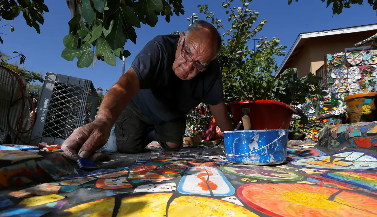 Gonzalo Duran menyusun pecahan keramik menjadi mozaik di salah satu sudut Mosaic Tile House Venice, California, AS, (26/9). Rumah ini dipenuhi mozaik dari kepingan keramik, genteng, souvenir, mainan hingga barang-barang bekas. (REUTERS/Mario Anzuoni)