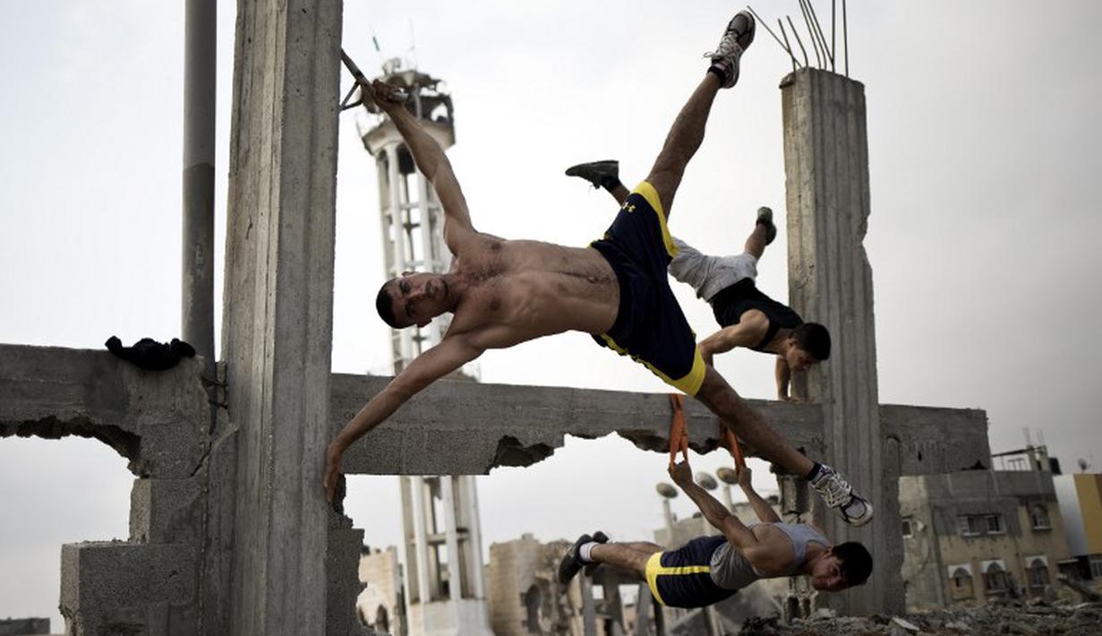 Anggota Bar Palestine, berlatih Street workout di bekas reruntuhan bangunan di kota Gaza, Palestina. Street workout adalah latihan yang dilakukan di luar ruang dengan memanfaatkan fasilitas yg ada. (AFP Photo/Mohammed Abed)