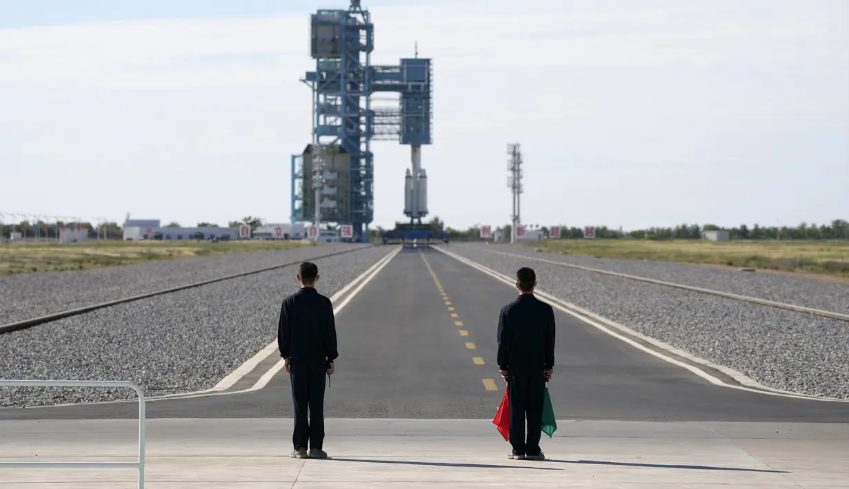 Para pejabat berdiri di landasan jelang peluncuran roket Long March-2F Y12 yang membawa pesawat ruang angkasa Shenzhou-12 di Pusat Peluncuran Satelit Jiuquan, China, Kamis (17/6/2021). Di stasiun ruang angkasa nanti, mereka akan melakukan tugas selama tiga bulan ke depan. (AP Photo/Ng Han Guan)
