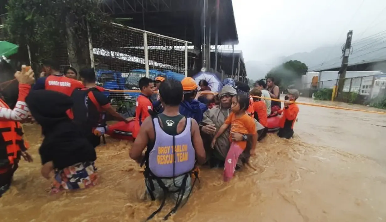 Penduduk sedang mengarungi banjir yang disebabkan oleh Topan Rai saat mereka dievakuasi ke tempat yang lebih tinggi di Kota Cagayan de Oro, Filipina selatan, Kamis (16/12/2021). (Philippine Coast Guard via AP)