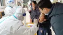 Seorang anak menjalani tes asam nukleat untuk virus corona Covid-19 di Anyang di provinsi Henan, China tengah pada 12 Januari 2022. China sedang berjuang melawan covid di beberapa kota, beberapa minggu sebelum Beijing menjadi tuan rumah Olimpiade Musim Dingin 2022. (STR/AFP)
