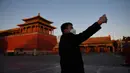 Seorang pria berswafoto di luar Kota Terlarang yang ditutup di Beijing pada Selasa (4/2/2020). Mencegah korban virus corona bertambah, China menutup  banyak destinasi wisata termasuk Kota Terlarang yang ditutup untuk kunjungan wisatawan sejak 24 Januari 2020 lalu. (GREG BAKER/AFP)