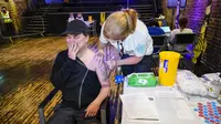 Drag queen Baga Chips disuntik vaksin Pfizer di pop-up pusat vaksinasi Covid yang didirikan di klub malam Heaven di London, Minggu (8/8/2021). Heaven menjadi klub malam pertama di Inggris yang diubah sebagai pop-up pusat vaksinasi untuk mengajak kaum muda agar mau divaksin (AP/Alberto Pezzali)