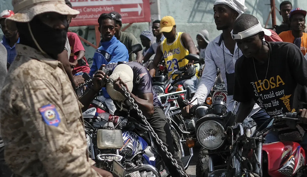 Pengendara sepeda motor mencoba masuk ke dalam pompa bensin saat terjadi kelangkaan bahan bakar nasional di Port-au-Prince, Haiti, Minggu (31/10/2021). Kelangkaan BBM membuat warga Haiti sulit mendapatkan transportasi dan memaksa sejumlah bisnis menghentikan operasi. (AP Photo/Matias Delacroix)