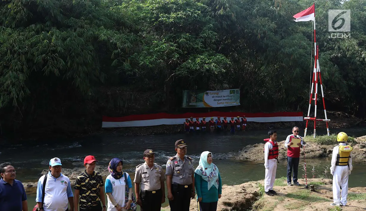 Komunitas Ciliwung bersama aparat  kepolisian mengikuti upacara bendera di Sungai Ciliwung, Jawa Barat, Jumat (17/8). Upacara di tengah aliran Sungai Ciliwung itu dalam rangka memperingati HUT ke-73 Republik Indonesia. (Liputan6.com/Immanuel Antonius)