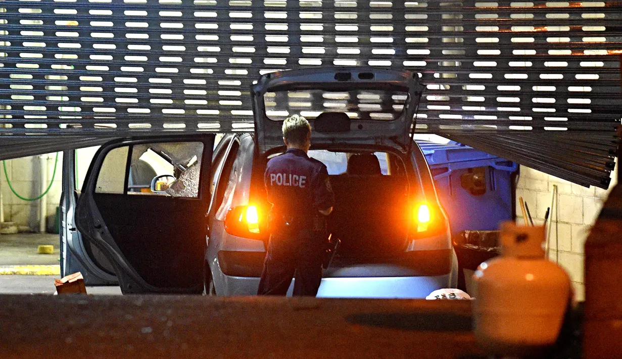 Petugas memeriksa mobil usai seorang pria dengan tabung gas di kendaraannya menabrak pintu gerbang markas polisi Merrylands, Sydney Barat, Kamis (21/7). Pria itu dilarikan ke RS dalam kondisi serius setelah kendaraannya terbakar (AAP/Sam Mooy via REUTERS)