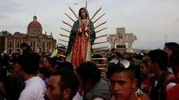 Sebuah patung Bunda dari Guadalupe diantara kerumunan peziarah di kawasan Basilika Guadalupe di Mexico City, Meksiko (11/12). Bunda dari Guadalupe adalah penampakan sosok Maria paling tua yang tercatat dalam sejarah agama Katolik. (Reuters/Henry Romero)
