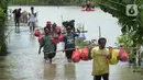 Warga berjalan melintasi banjir di Desa Sindangsari, Kabupaten Bekasi, Jawa Barat, Rabu (24/2/2021). Tim Tanggap Bencana Land Rover Club Indonesia (LRCI) melakukan drop logistik dan mengevakuasi warga yang sakit di Desa Sindangsari. (merdeka.com/Imam Buhori)