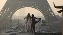 Model seksi ini bergaya di depan menara Eiffel saat matahari terbit dalam sesi pemotretan, Paris (11/3/2016). (AFP/Ludovic MARIN)