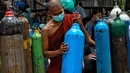 Seorang biksu Buddha yang mengenakan masker memegang tangki oksigen untuk diisi ulang di luar pabrik oksigen Naing di zona industri South Dagon di Yangon, Myanmar, Rabu (28/7/2021). (AP Photo)