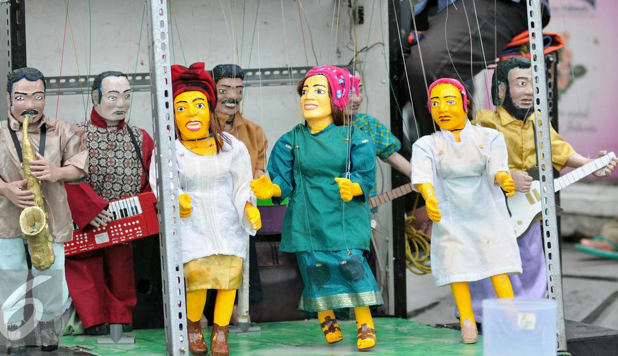 Delapan boneka yang digantukan pada tuas terlihat menari mengikuti alunan musik dangdut, bergoyang menghibur anak-anak di pelataran Museum Fatahillah, Jakarta, Kamis (17/12/2015). (Liputan6.com/Yoppy Renato)