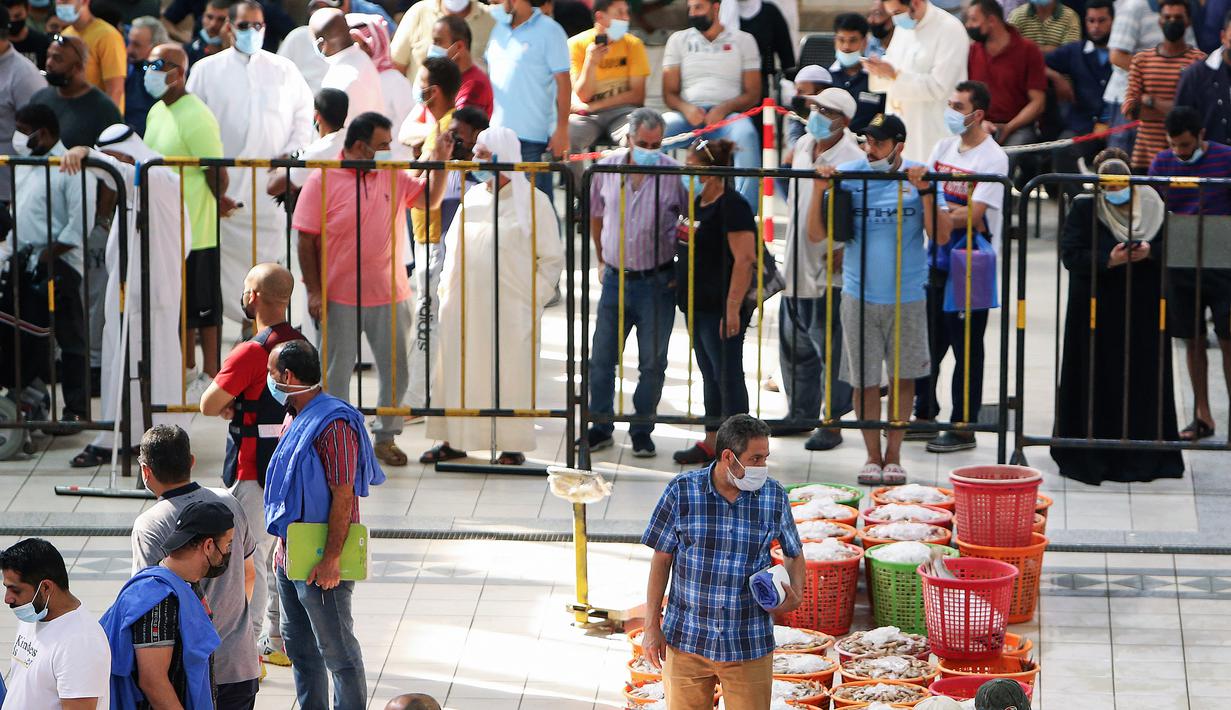 Orang-orang berbelanja selama pelelangan di pasar ikan di Kuwait City (8/8/2021). Pelelangan dibuka kembali di negara itu setelah enam bulan ditutup di tengah pandemi virus corona. (AFP/ Yasser Al-Zayyat)