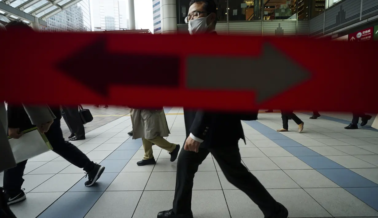 Penumpang kereta mengenakan masker berjalan selama jam sibuk di Stasiun Shinagawa di Tokyo, Senin (22/3/2021). Perdana Menteri Jepang Yoshihide Suga pada Senin mencabut keadaan darurat virus corona di Tokyo dan tiga prefektur lainnya yang tersisa. (AP Photo/Eugene Hoshiko)