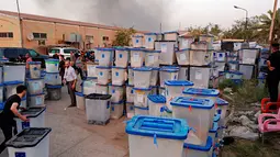 Sejumlah petugas menyelamatkan kotak suara saat kebakaran gudang surat suara terbesar Irak di Baghdad, Minggu (10/6). Penyebab kebakaran di gudang penyimpanan itu juga masih belum jelas. (AP/Karim Kadim)