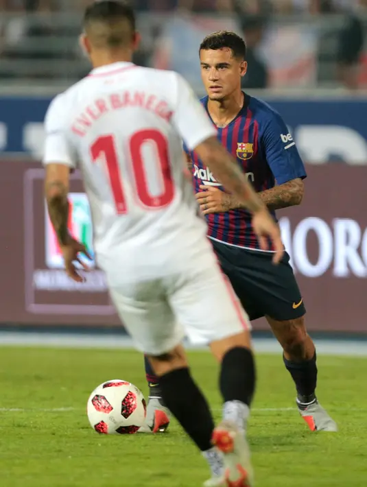 Gelandang Barcelona, Philippe Coutinho menggiring bola dari kawalan gelandang Sevilla pada pertandingan  Piala Super Spanyol di Tangier, Maroko, (13/8). Barcelona berhasil mengalahkan Sevilla dengan skor 2-1. (AP Photo/Mosa'ab Elshamy)