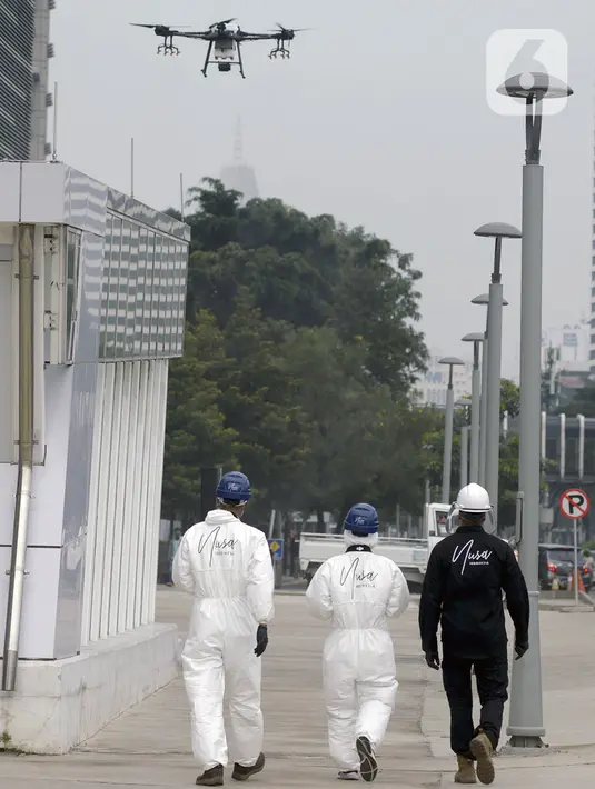 Petugas menggunakan drone saat menyemprotkan cairan disinfektan di Jalan Bursa Efek menuju Patung  Pemuda, Jakarta, Jumat (27/3/2020). Penyemprotan dilakukan untuk mencegah penyebaran virus corona COVID-19. (merdeka.com/Imam Buhori)