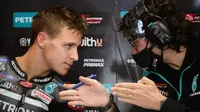 Pembalap Petronas Yamaha, Fabio Quartararo, berbincang dengan teknisinya usai latihan bebas MotoGP Catalunya di Circuit de Barcelona-Catalunya, Jumat (25/9/2020). Pembalab Yamaha, Morbidelli, finish pertama dengan catatan waktu satu menit 39,789 detik. (AFP/Lluis Gene)