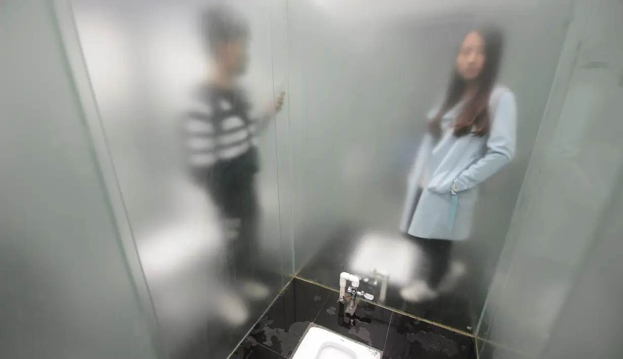 Dua pengunjung berpose saat berada di toilet umum transparan di sebuah taman di Changsha, Provinsi Hunan, Tiongkok, (29/9). Toilet umum ini dibuat dari kaca transparan untuk menarik wisatawan.. (REUTERS/Stringer)
