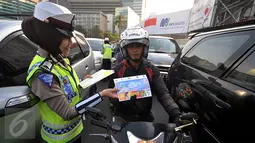 Polisi wanita dari Polda Metro Jaya membagikan peta mudik 2015 kepada pengendara di kawasan Bundaran HI, Jakarta, Jumat (26/6/2015). Pembagian peta tersebut diharapkan mampu meningkatkan keselamatan dalam bermudik. (Liputan6.com/Johan Tallo)