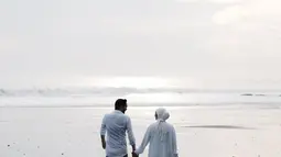 Nikmati keindahan pantai sembari jalani pemotretan pasangan ini makin terlihat romantis. Berpegangan tangan sambil tatapan mesra, jepretan foto ini mempelihatkan kehangatan hubungan Aryani Fitriana dan Donny Michael. Suasana pantai dengan deburan ombak membuat suasana sekitar makin syahdu. (Liputan6.com/IG/@aryanifitriana24)