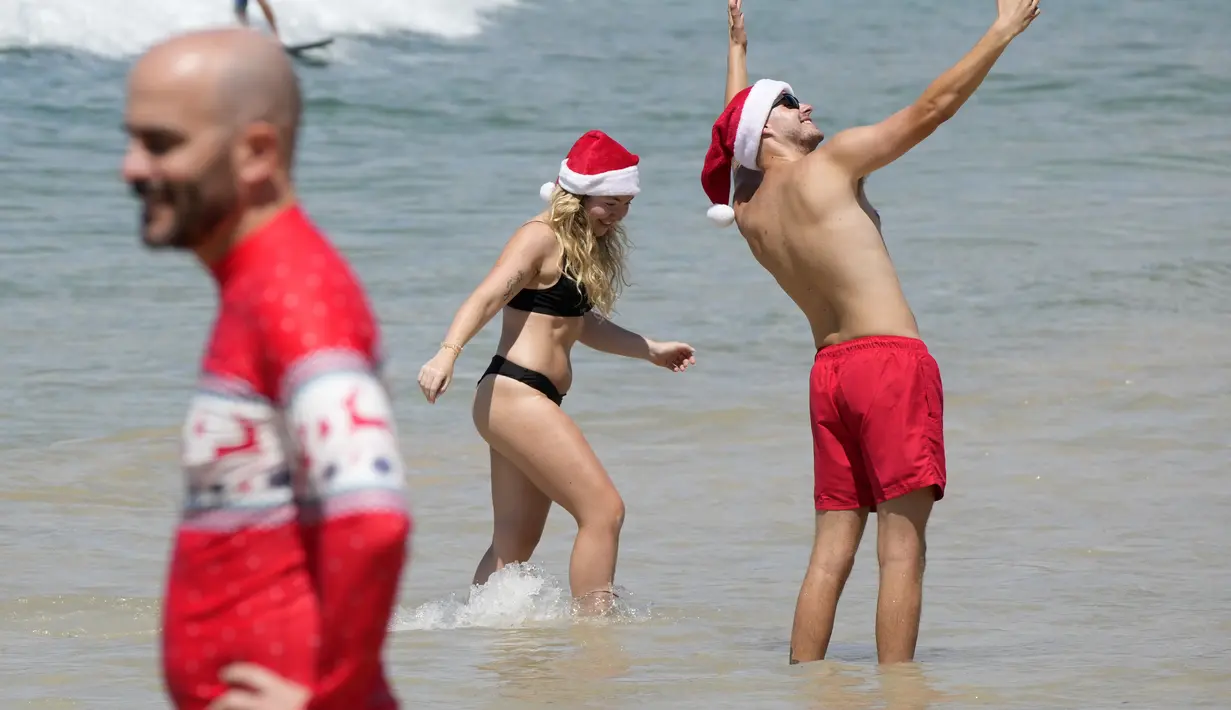 Topi Santa, jumper bertema Natal, dan bikini merah terlihat sejauh mata memandang di sepanjang pantai yang terkenal ini.  (AP Photo/Rick Rycroft)