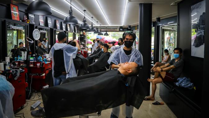 Penata rambut melayani pelanggan di sebuah salon yang dibuka kembali saat pelonggaran beberapa langkah pengendalian karena Virus Corona COVID-19 di Bangkok, Minggu (3/5/2020). Pemerintah Thailand mulai melonggarkan aturan pembatasan pergerakan orang dan pertemuan. (VIVEK PRAKASH/AFP)