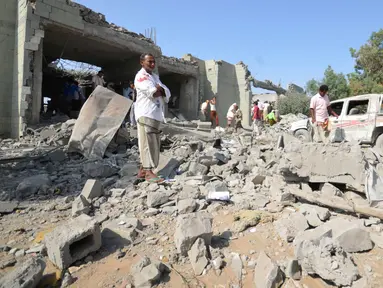 Sejumlah orang berdiri di puing penjara al-Zaydiyah yang hancur terkena serangan jet tempur koalisi pimpinan Arab Saudi di Yaman, Minggu (30/10). Menurut sejumlah sumber medis, puluhan orang tewas dalam serangan itu. (REUTERS/Abduljabbar Zeyad)