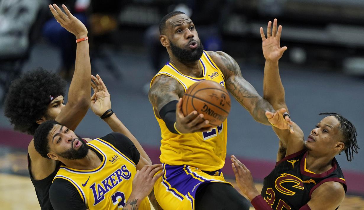 Pebasket LA Lakers, LeBron James (tengah) berusaha memasukkan bola dalam laga lanjutan babak reguler NBA melawan Cleveland Cavaliers di Quicken Loans Arena, Selasa (26/1/2021). (Foto: AP Photo/Tony Dejak)
