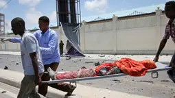 Sejumlah pria membawa korban yang tewas akibat serangan bom mobil di sebuah restoran di Mogadishu, Somalia, Rabu (5/4). Ledakan bom mobil tersebut telah menewaskan sejumlah orang. (AP Photo / Farah Abdi Warsameh)