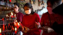 Warga etnis Tionghoa mengenakan masker berdoa untuk merayakan Tahun Baru Imlek di Bali, Selasa (1/2/2022). Orang-orang di seluruh Asia bersiap untuk perayaan Imlek yang diredam di tengah kekhawatiran atas virus corona dan varian omicron yang mulai merajalela. (AP Photo/Firdia Lisnawati)