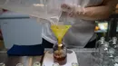 Seorang karyawan menuangkan minuman ExtraGineca, minuman yang terinspirasi oleh vaksin virus corona Covid-19, ke dalam botol kosong di sebuah bar koktail di George Town di pulau Penang, Malaysia (8/9/2021). (AFP/Mohd Rasfan)