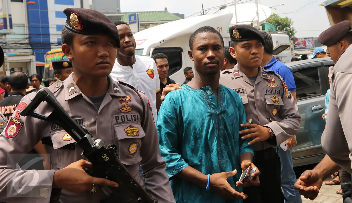 Polisi bersenjata dan BNN mengamankan Warga Negara Asing (WNA) saat melakukan razia di kawasan Petamburan, Jakarta, Jumat (29/1). Diduga razia tersebut terkait kasus penggerebekan sabu ratusan kilogram di Jepara. (Liputan6.com/Herman Zakharia)