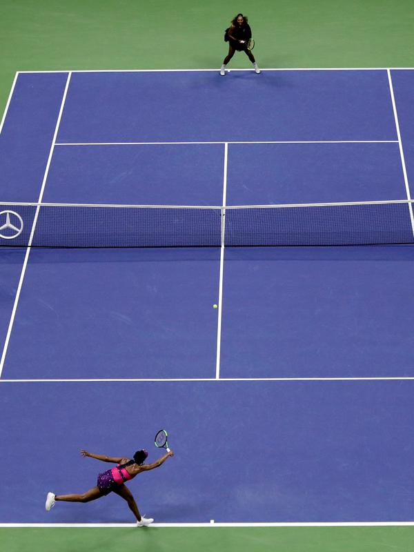 Petenis Venus Williams (bawah) mengembalikan bola kepada adiknya, Serena Williams (atas) selama putaran ketiga turnamen tenis AS Terbuka, di New York, Jumat (31/8). Venus kalah dari Serena. (AP Photo/Julio Cortez)