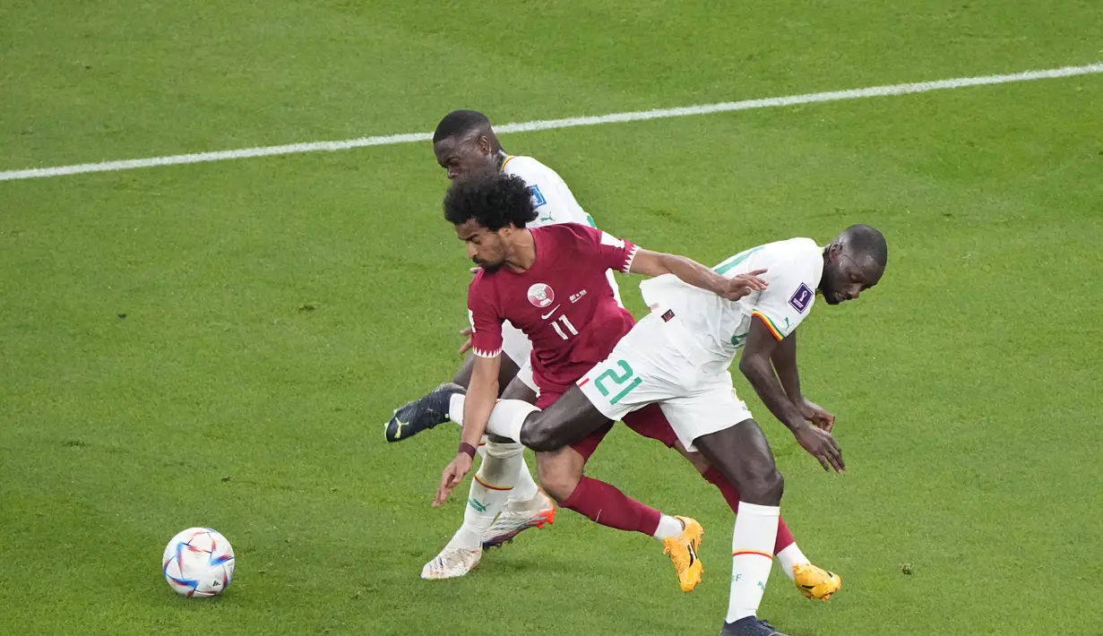 Penyerang Qatar, Akram Afif berusaha melewati dua pemain Senegal selama pertandingan grup A Piala Dunia 2022 di Stadion Al Thumama di Doha, Qatar, Jumat (25/11/2022). Sementara Qatar harus gigit jari lantaran hampir dipastikan gagal lolos ke fase gugur.  (AP Photo/Ariel Schalit)
