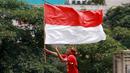 Seorang masyarakat membawa bendera Merah Putih saat menyambut Timnas Indonesia U-22 dan kontingen Indonesia untuk SEA Games 2023 saat pawai Kira87uara yang berlangsung dari Kemenpora hingga GBK, Jakarta, Jumat (19/05/2023). (Bola.com/M Iqbal Ichsan)