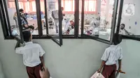 Para murid mengintip rekan mereka disuntik vaksin COVID-19 di SDN Cempaka Putih Timur 03 Pagi, Jakarta, Selasa (14/12/2021). Vaksinasi untuk anak usia 6-11 tahun dilakukan secara bertahap dengan target 26,7 juta anak. (merdeka.com/Iqbal S. Nugroho)