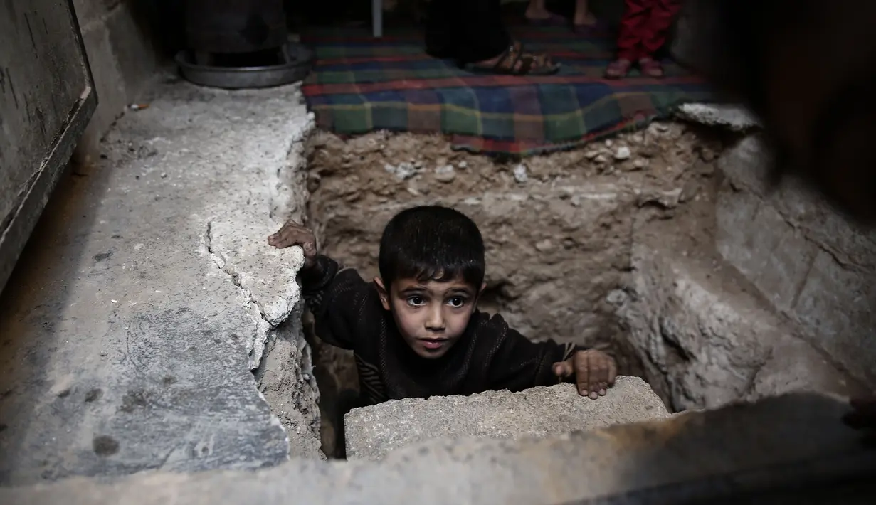 Seorang bocah berada di lubang menuju ruang bawah tanah Abu Omar di Douma, Damaskus, Suriah, (30/10). Abu Omar dibantu tetangganya berhasil menggali dan membangun ruangan di kedalaman 4 meter dari permukaan tanah. (AFP PHOTO/Sameer Al-Doumy)