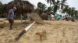 Seorang pedagang bekerja di tengah puing-puing usaha kecilnya berupa penyewaan payung dan makanan setelah diterjang Badai Fiona di pantai di Punta Cana, Republik Dominika (19/9/2022). Badai Fiona datang dengan membawa hujan lebat dan angin kencang di Republik Dominika. (AP Photo/Ricardo Hernandez)